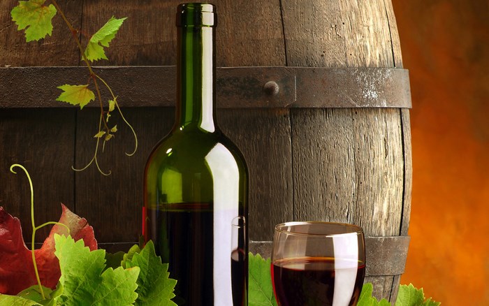 Wine bottle and glass near wooden barrel