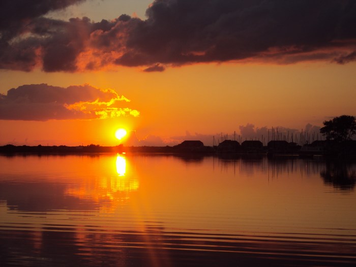 Sunset over a calm bay with boats and houses