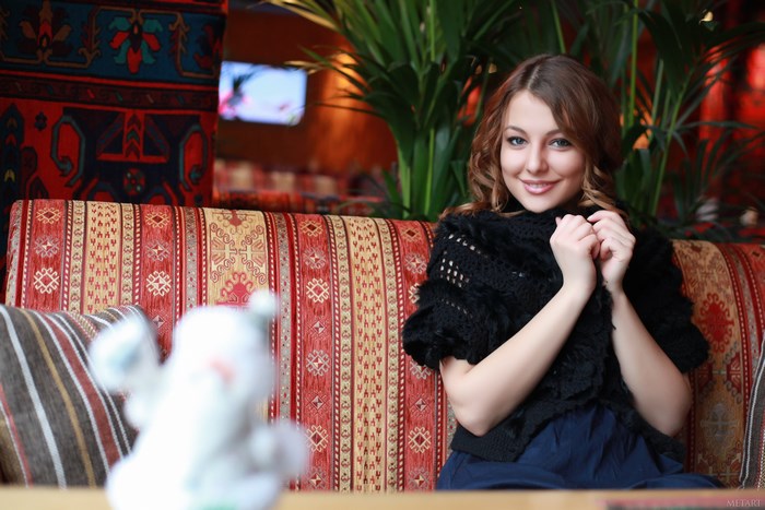 Smiling Woman Sitting on Patterned Sofa