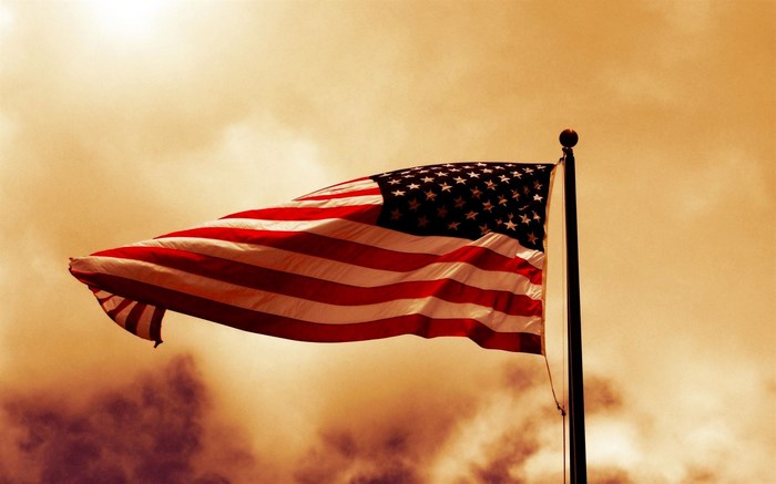 American flag waving on a flagpole against a cloudy sky