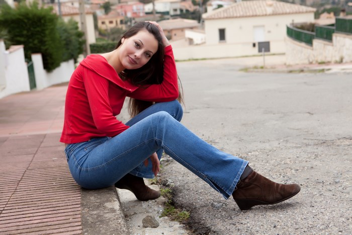 Lorena Garcia Wearing Red Sweater on Street Curb