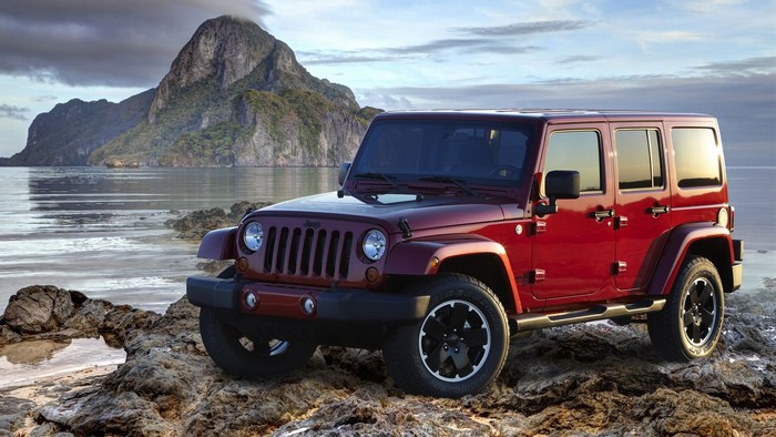 Red Jeep Wrangler on Rocky Beach with Mountains