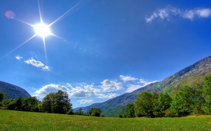 Sunny day over a green meadow and mountains