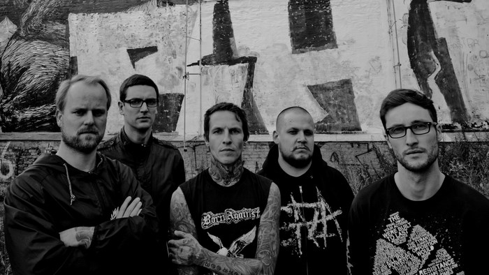 Band members posing in front of graffiti wall