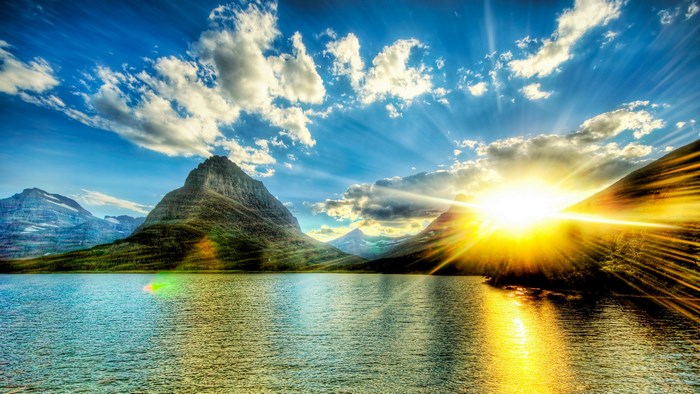 Sunrise over a mountain lake with sun rays