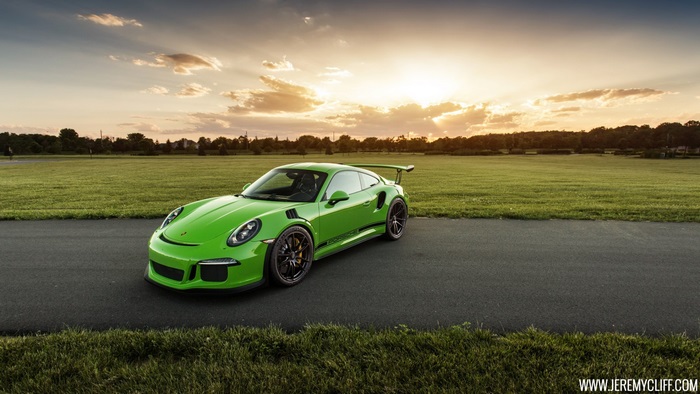 Green Porsche 911 GT3 RS on a road at sunset