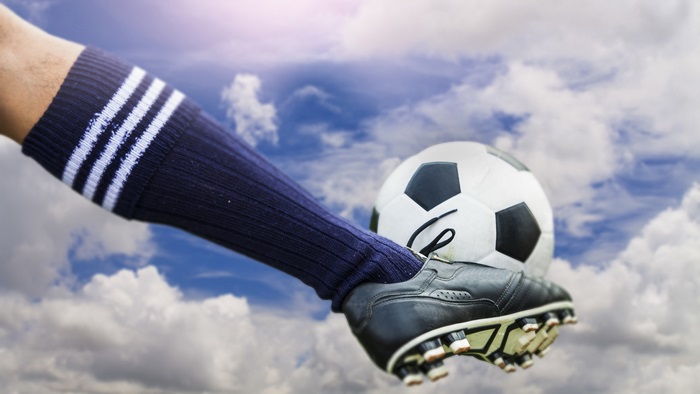 Football being kicked against a cloudy sky