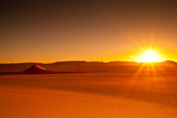 Desert landscape at sunset with sunburst
