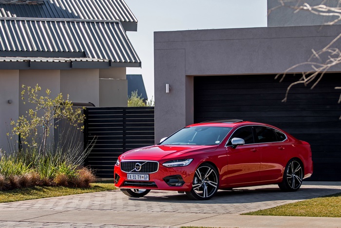 Red Volvo S90 parked in front of a modern house