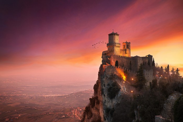 Castle on Rocky Cliff at Sunset with Birds
