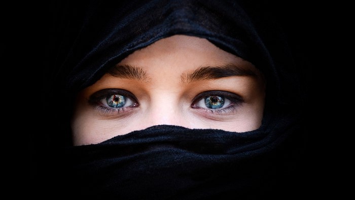 Close-up of a woman's blue eyes wearing a black hijab