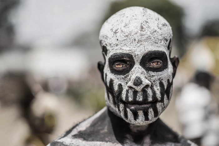 Man with skull face paint in traditional African attire