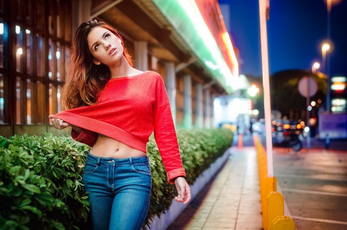 Woman in red top and jeans looking up at night