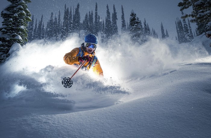 Skier in yellow jacket carving powder