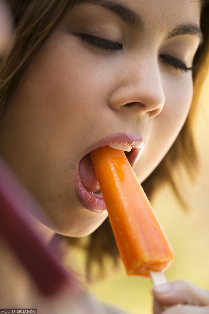 Woman eating an orange popsicle