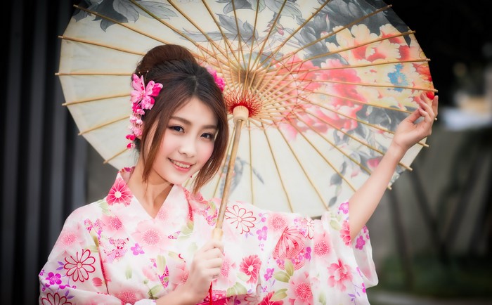 Woman in a pink kimono holding a floral umbrella
