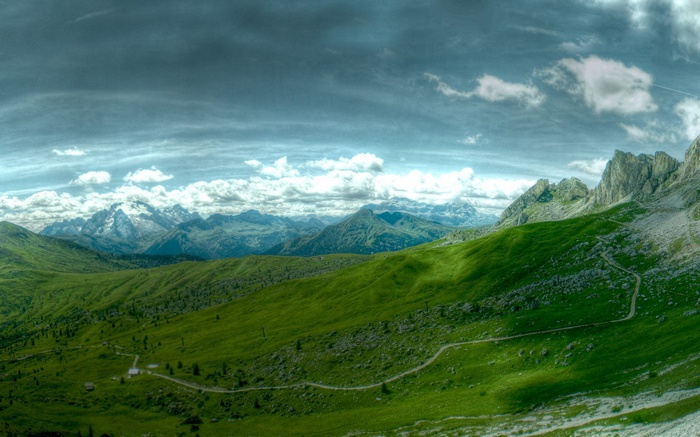 Panoramic view of green mountain slopes and rocky peaks under a cloudy sky