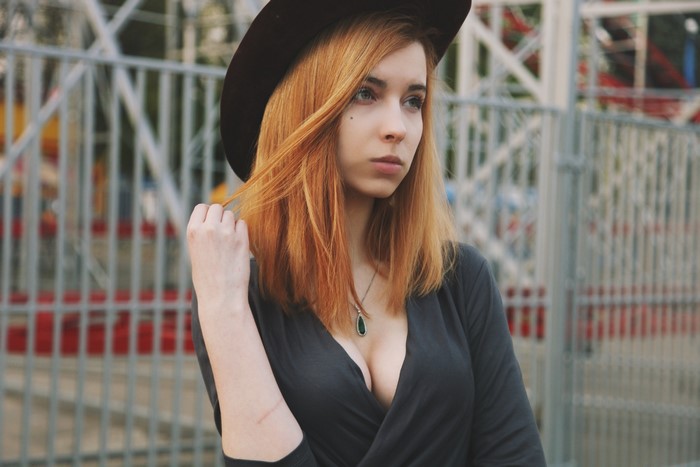 Woman with red hair wearing a hat and necklace