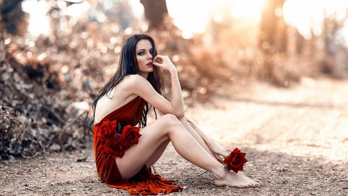 Woman in Red Dress Sitting Outdoors with Roses
