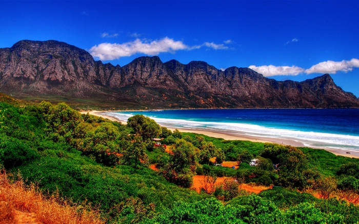 Mountain range overlooking a beach and green hills