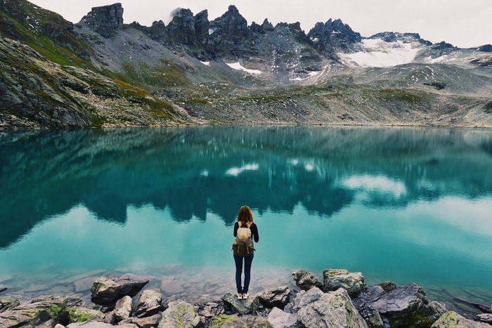 Woman with backpack overlooking turquoise mountain lake