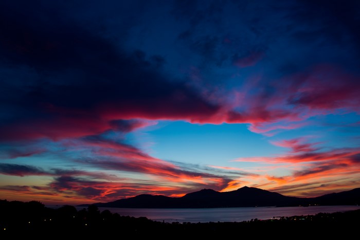 Sunset over the sea with colorful clouds and mountains