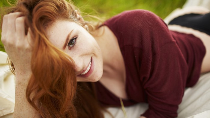 Redhead woman with freckles lying down