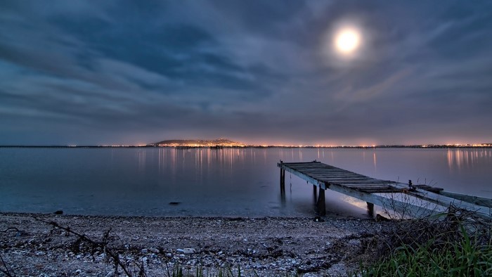 Night scene with moon over water and a wooden pier