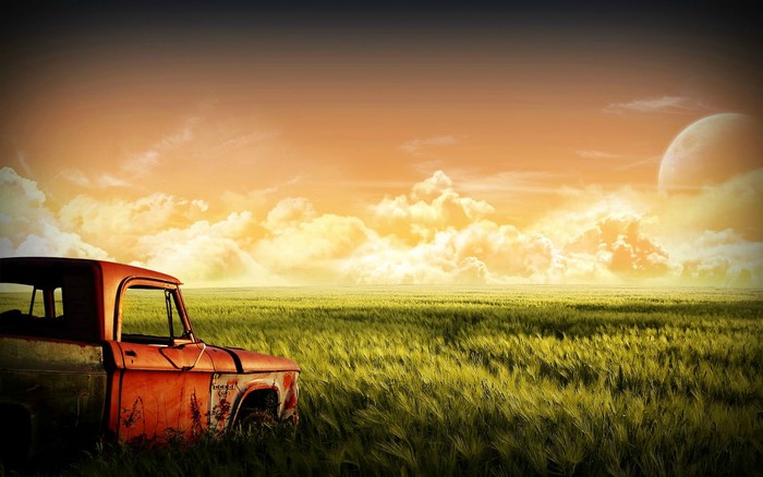Rusty truck in a field at sunset