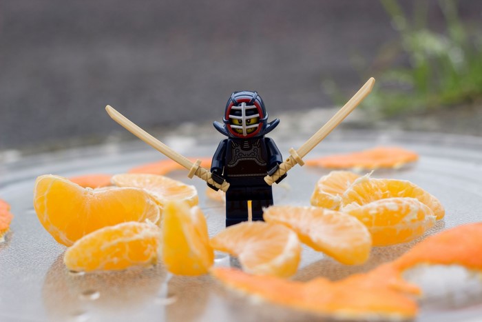 Lego ninja with katanas surrounded by tangerine slices