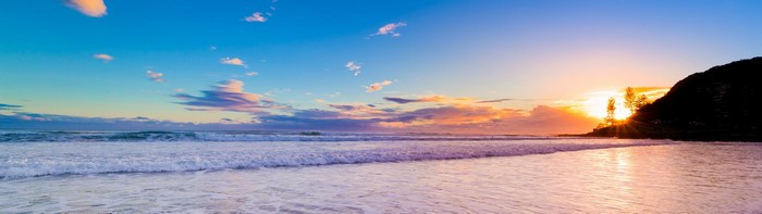 Beach sunset with waves and a hill