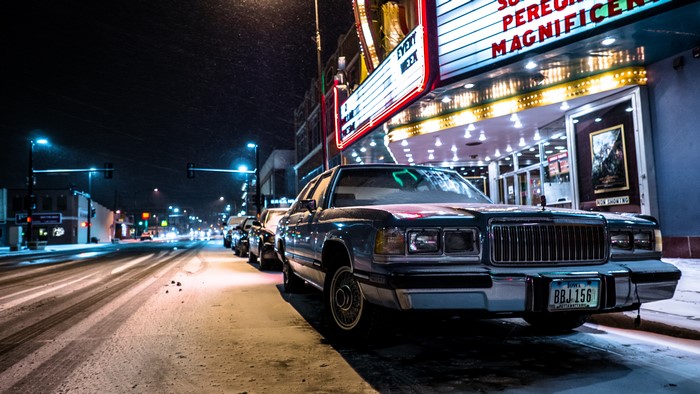 Car parked in front of a movie theater at night in winter