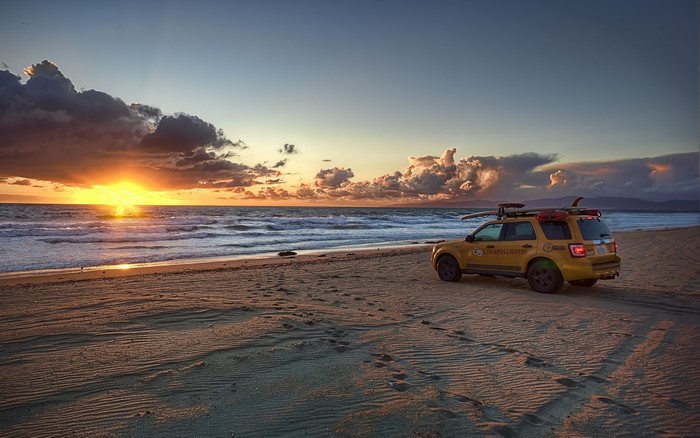 Lifeguard SUV on beach at sunset