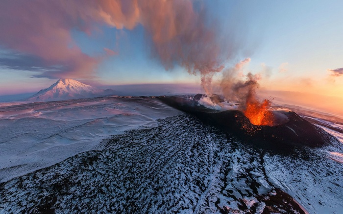 Volcano erupting with lava and smoke in a snowy landscape