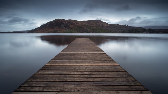 Wooden pier on a calm lake with mountains in the background
