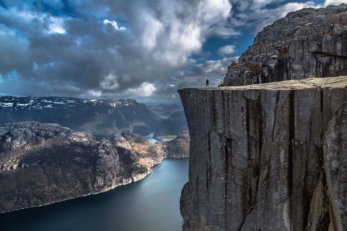 Man standing on Preikestolen cliff overlooking Lysefjord, Norway