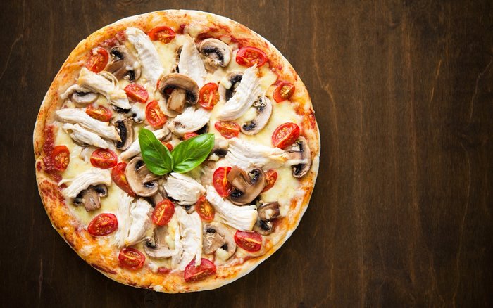Pizza with chicken, mushrooms, tomatoes, and basil