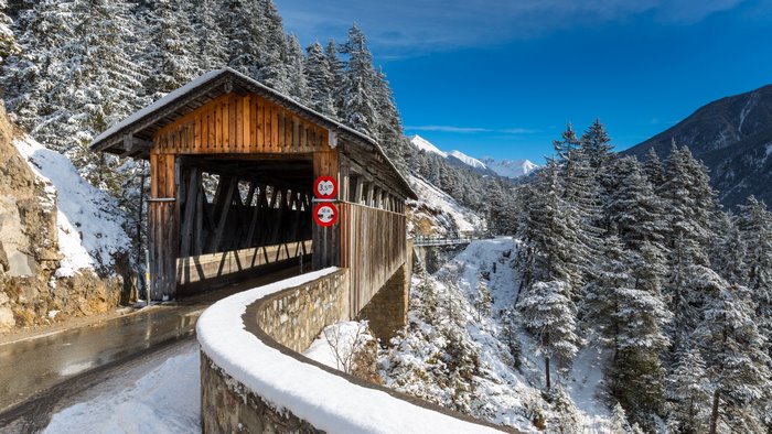Covered wooden bridge in snowy Swiss Alps