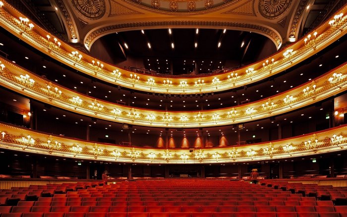 Grand opera house interior with red seats and ornate balconies