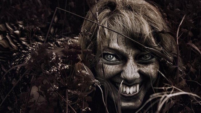 Vampire woman with fangs in dark woods