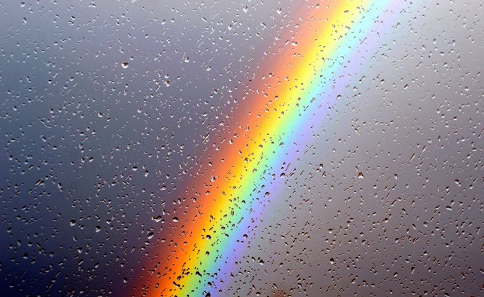 Rainbow over water drops on glass