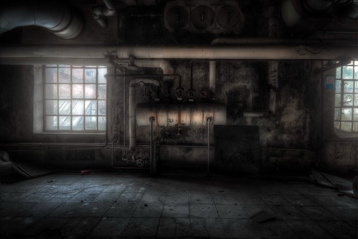 Abandoned industrial room with pipes and windows