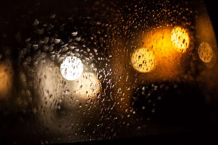 Raindrops on glass with bokeh lights at night