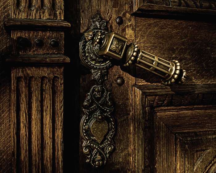 Antique brass door handle on a rustic wooden door