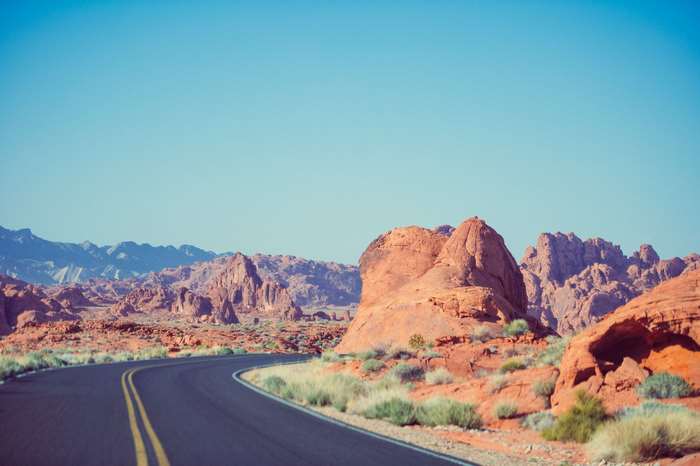 Desert road curving through rocky landscape with mountains
