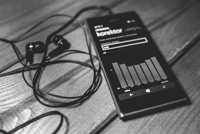 Black and white image of earbuds and a Windows Phone