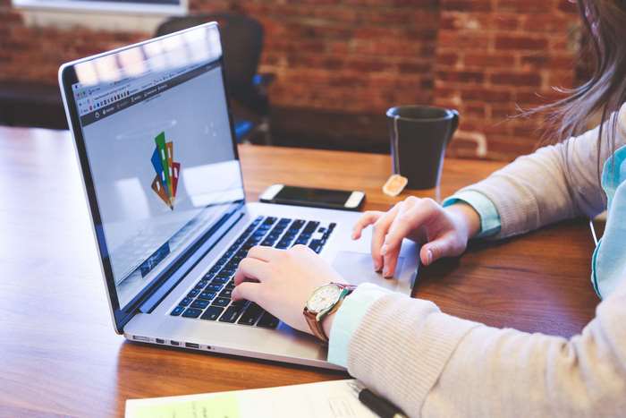 Woman working on a MacBook Pro with a cup and phone