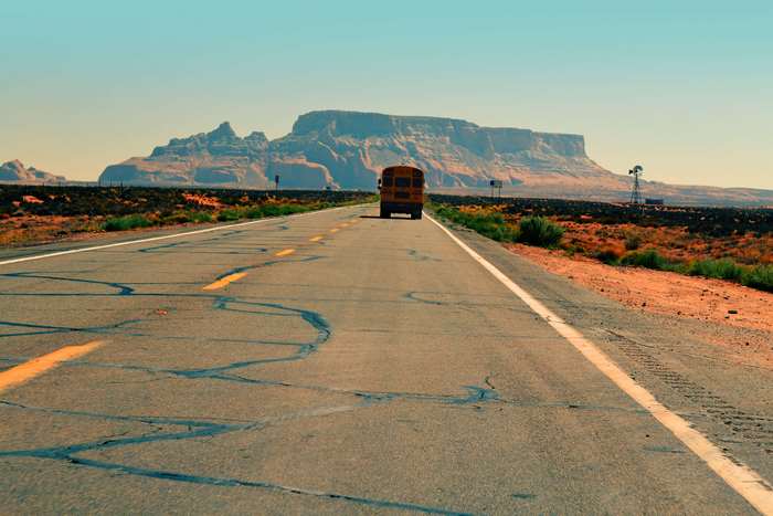Yellow school bus on a desert road in Utah 4K