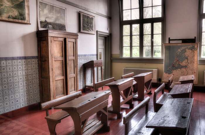 Old classroom with desks, map, and wooden cabinet