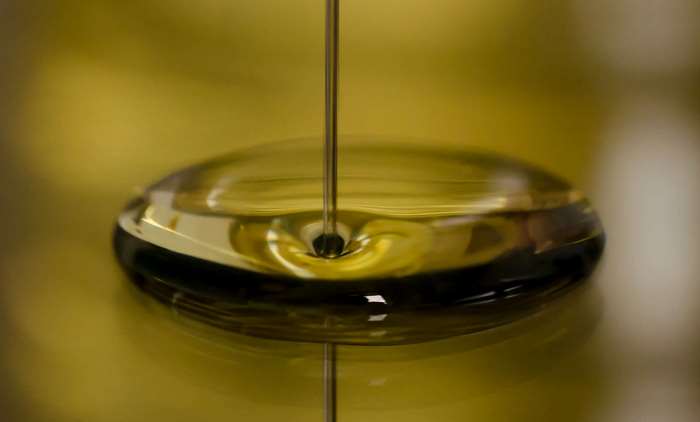 A thin stream of oil falling into a pool of oil
